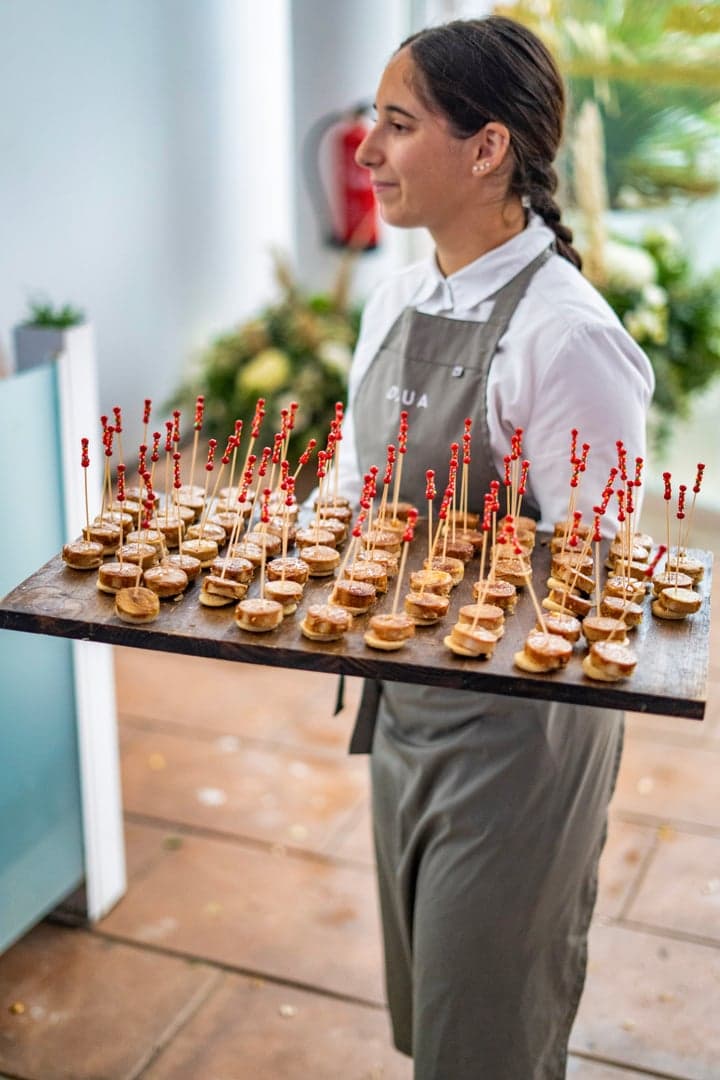 Een serveerster van Dalua draagt een schaal met miniburgers tijdens het welkomstdrankje.