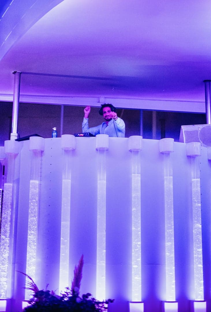 DJ Armin Zamani stuurt de muziek vanuit een verlicht DJ-booth.